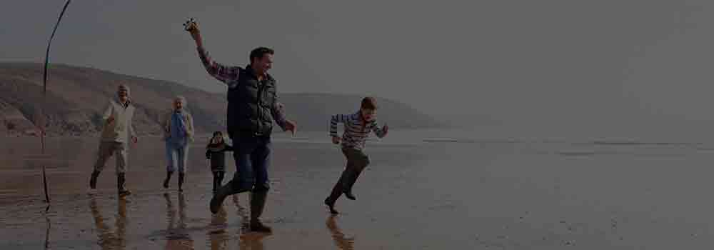 Family Running On a Beach Together With a Kite